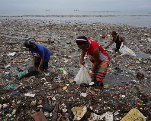 July 28, 2018 - Manila, Philippines - July 28, 2018 Manila, Philippines. Scavengers collect recyclable items from the garbage washed along the coast of Manila Bay after days of continous rain, Saturday. Tons of plastic waste have been polluting the ocean every year.
